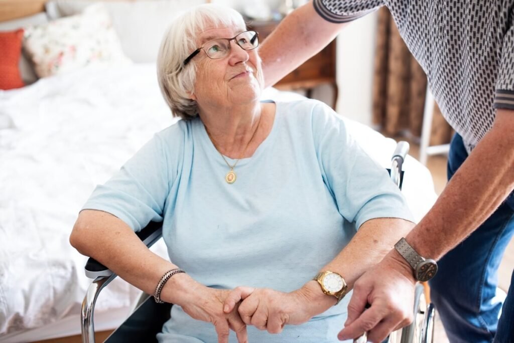 Elderly woman in wheelchair helped by caregiver