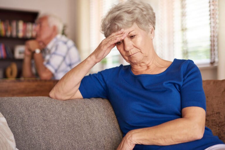 Stressed caregiver with loved one in background