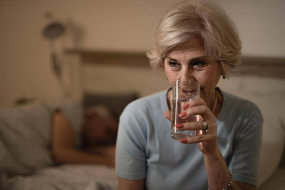 Elderly woman drinks a glass of water.