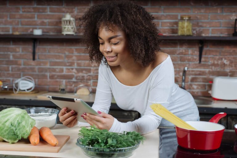 Caregiver prepares a nutritious meal with tablet in hand.