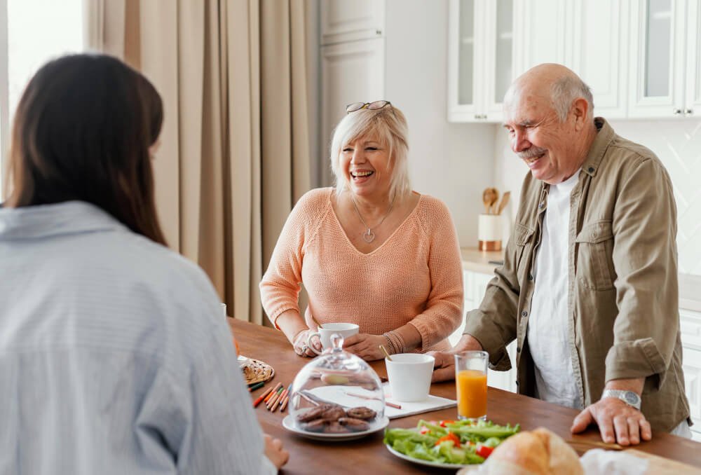 Caregiver shares a meal with elderly couple.