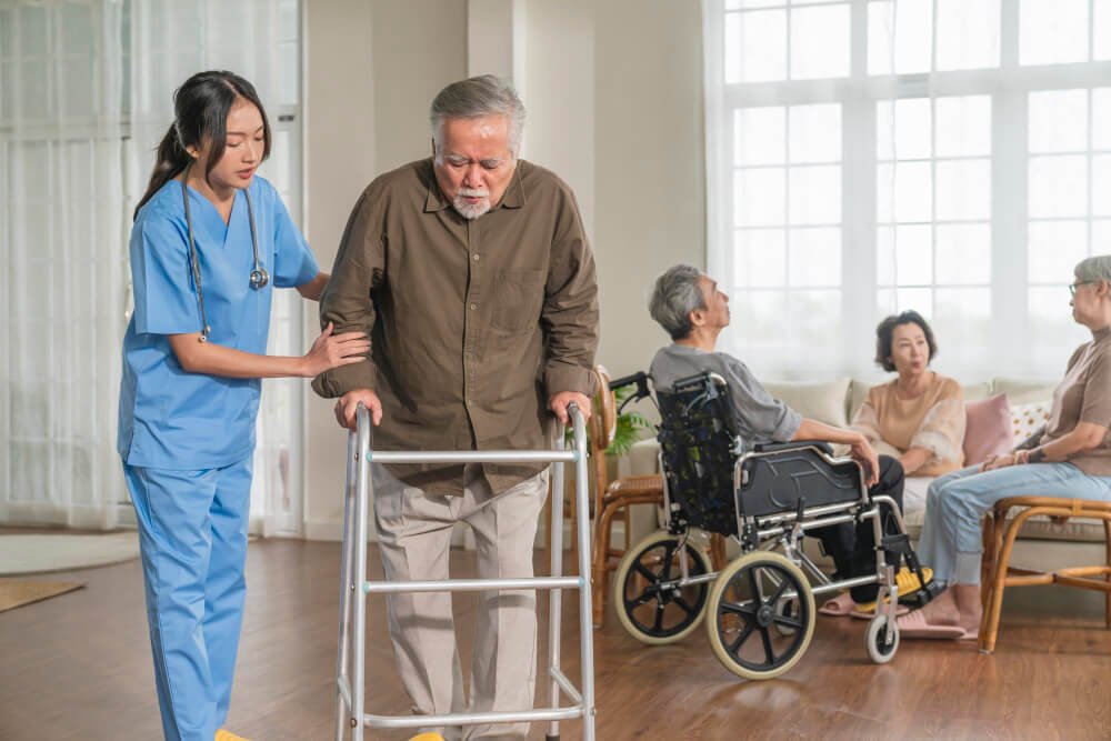 Professional caregiver helps elder male patient in nursing home.