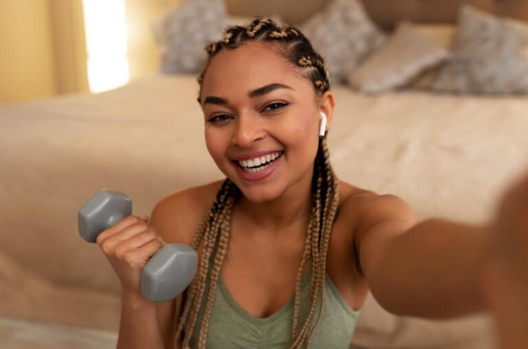 Close-up of young woman taking a selfie with a dumbbell in her hand
