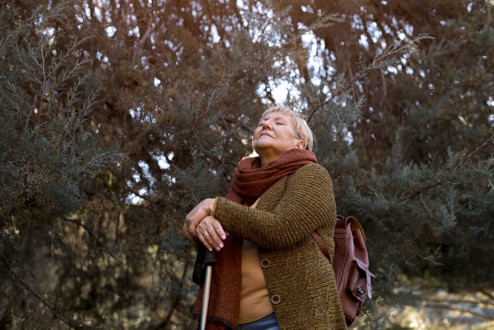 Senior woman pauses while walking to enjoy nature.