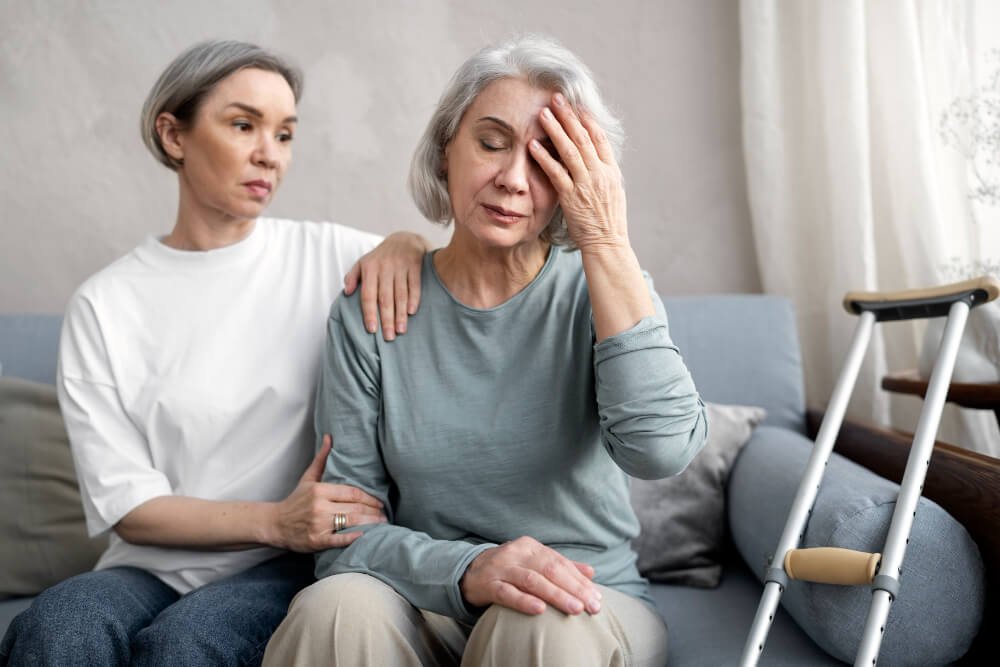 middle aged woman comforts senior woman with crutches