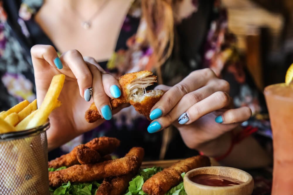 Woman eating fried chicken strips and fries