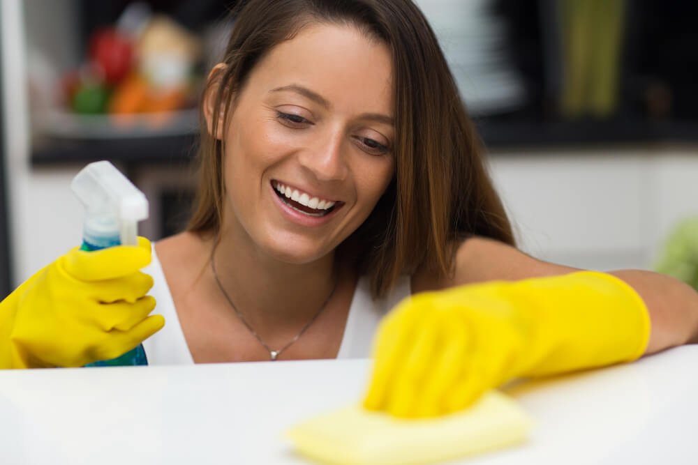 Young woman with spray bottle cleans countertop
