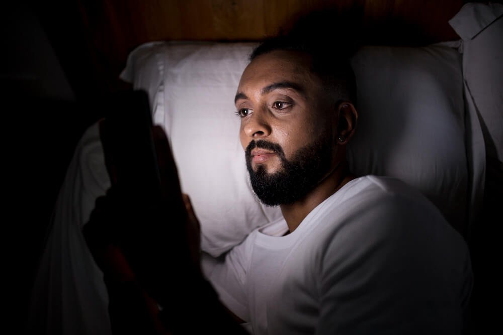 sleepless man viewing social media in bed