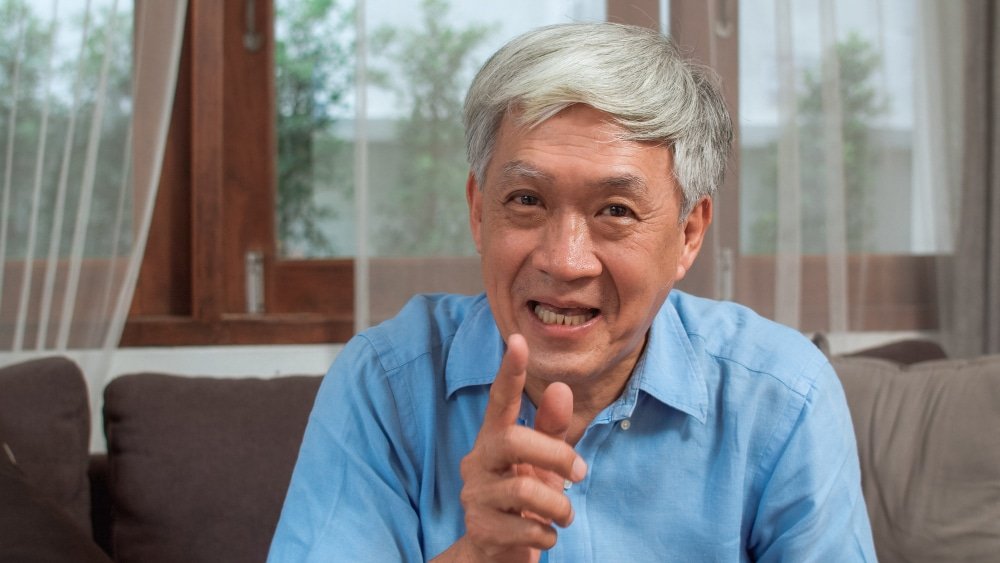 annoyed elderly man points finger at viewer