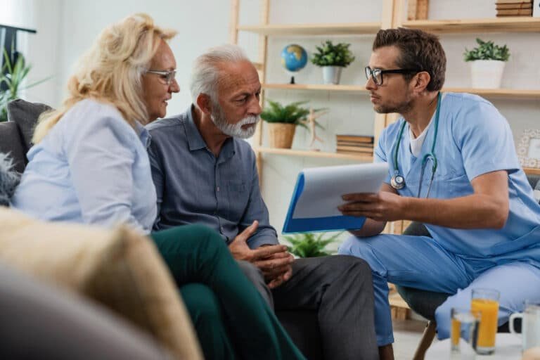 doctor with clipboard speaks to elderly couple