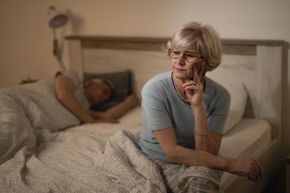 thoughtful senior woman sits at bedside