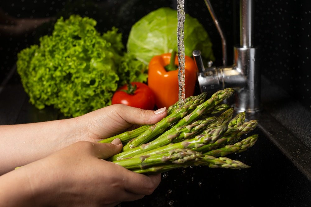 Woman washes vegetables at sink