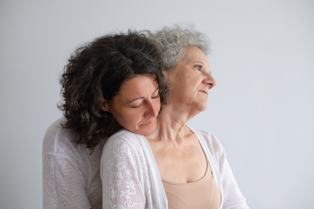 middle-aged woman hugs her mother who has dementia