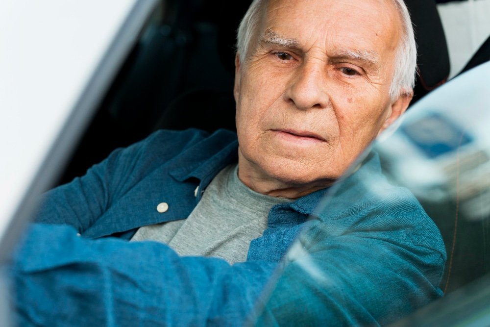 elderly man behind the wheel of a car