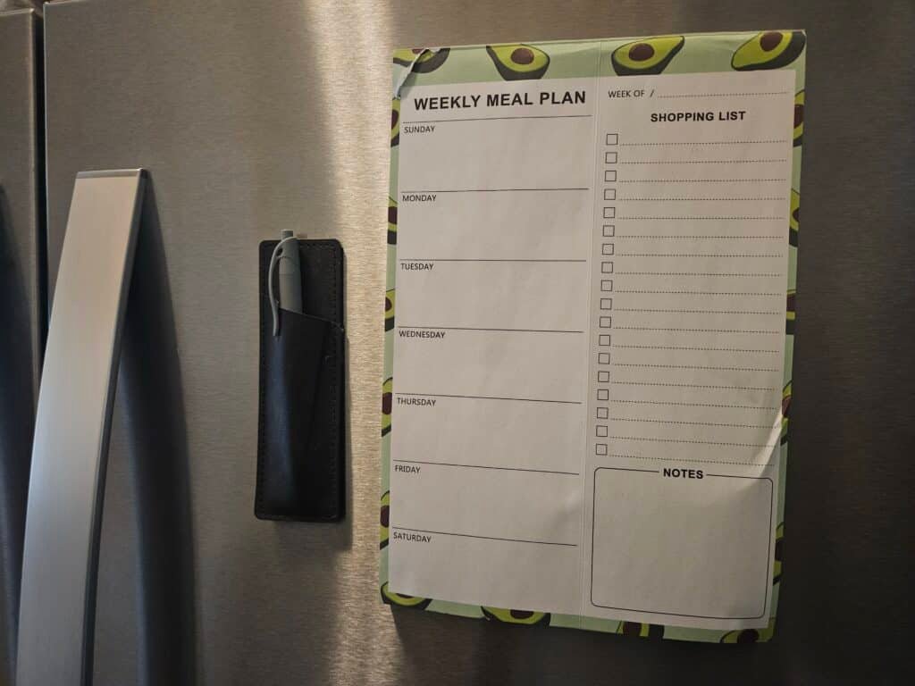 meal planner pad with shopping list on fridge
