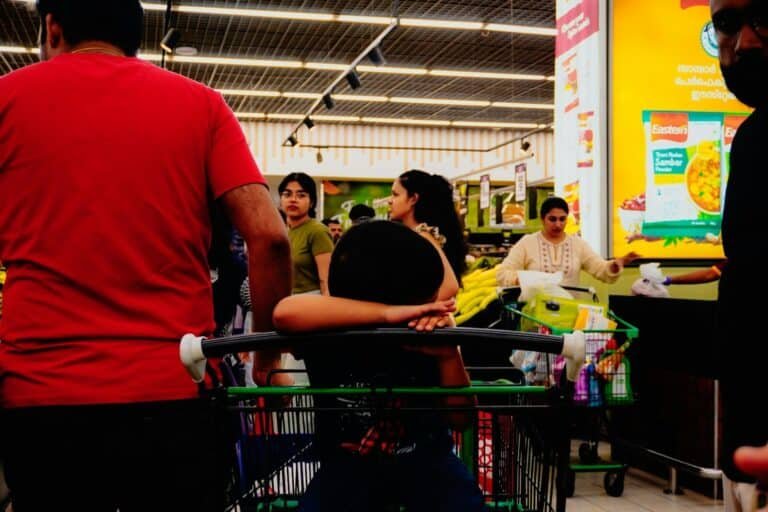People shopping in a brightly lit supermarket aisle.