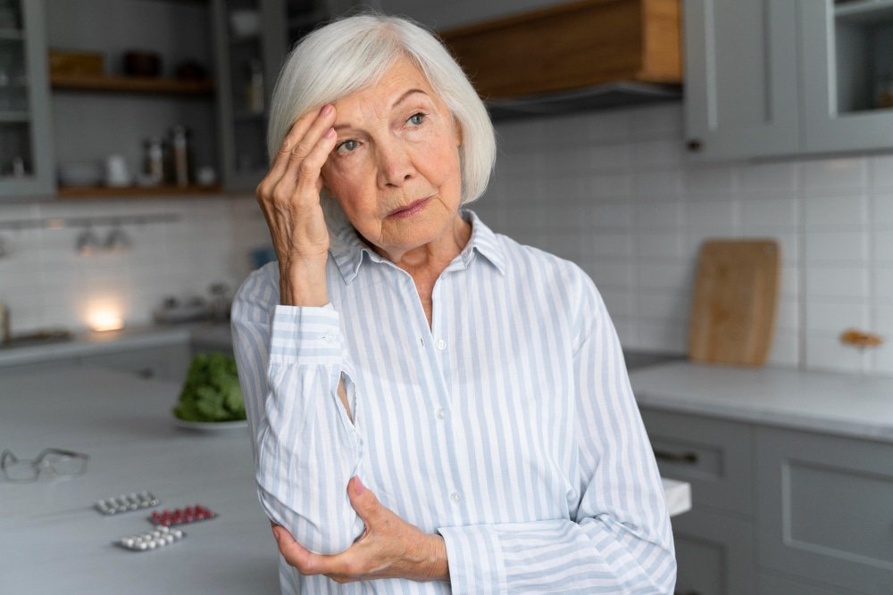 senior woman with dementia stands in kitchen
