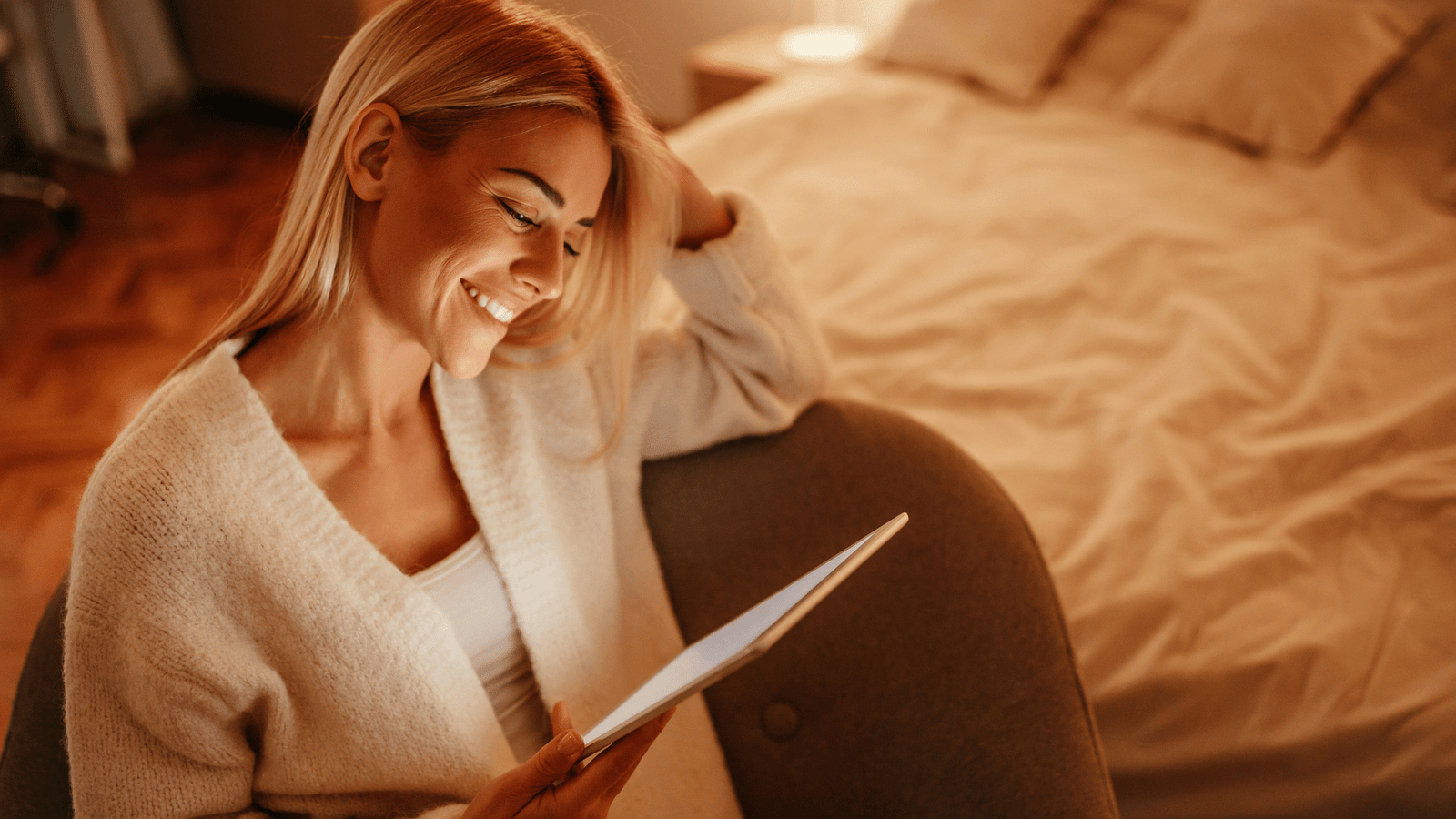 woman relaxes while reading next to her bed