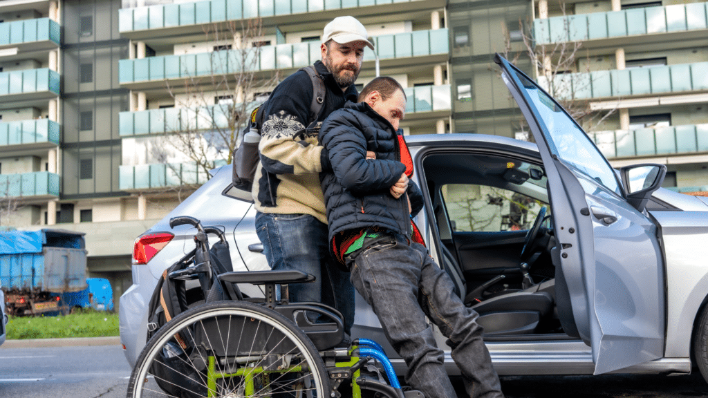 caregiver transfers disabled man from wheelchair into car