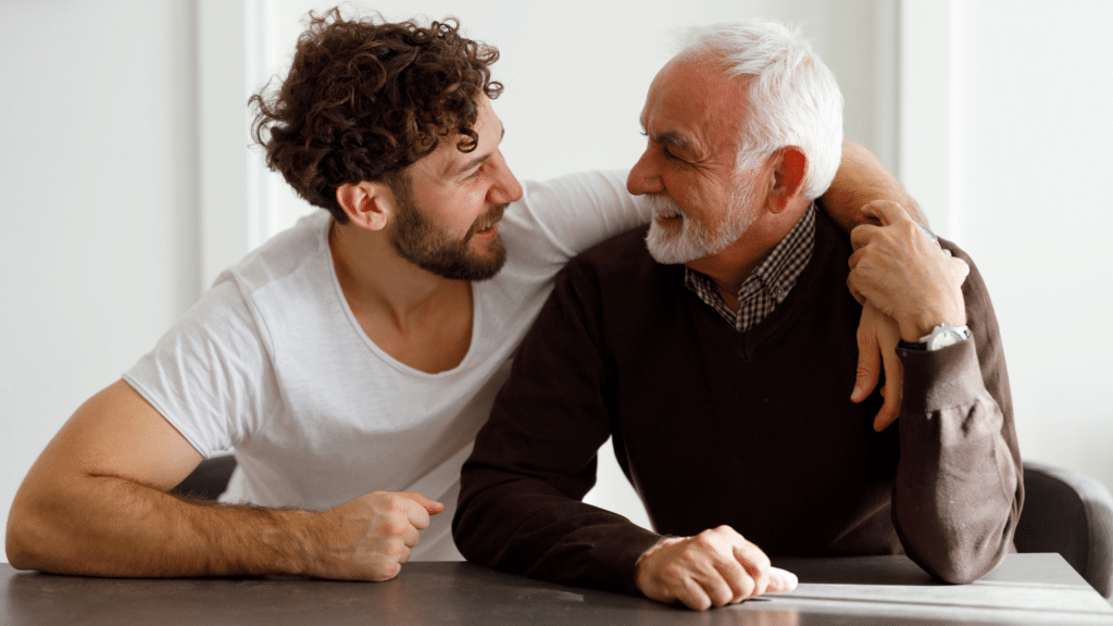 smiling male caregiver with his senior father