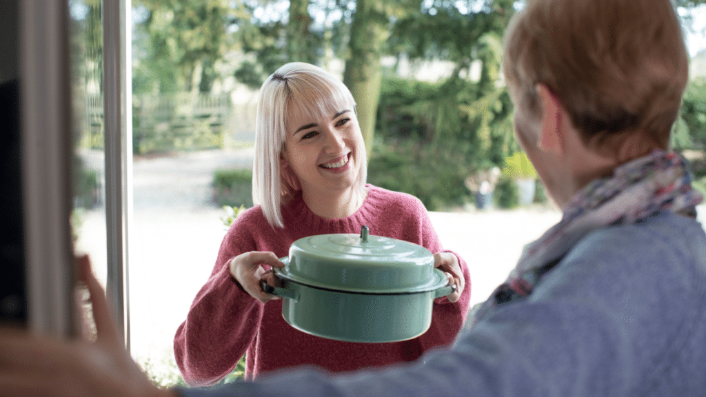 caregiver helper brings dinner to elderly woman